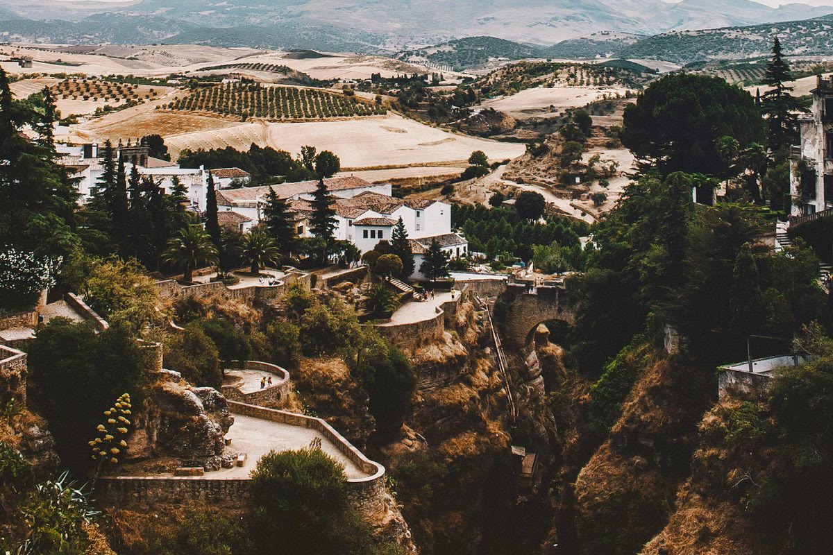 Jardins en terrasses au bord du Tajo de Ronda, avec l'un de ses ponts anciens et la plaine au fond